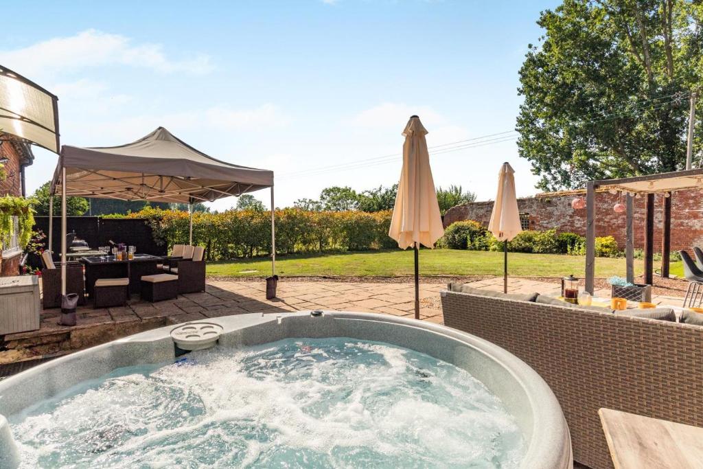 a hot tub in a yard with umbrellas at 4 Bed in East Harling oc-m31907 in East Harling