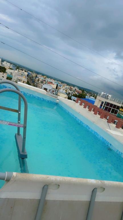 a large swimming pool with a view of the ocean at Sofra service apartment by LUXE with swinging pool in Mysore