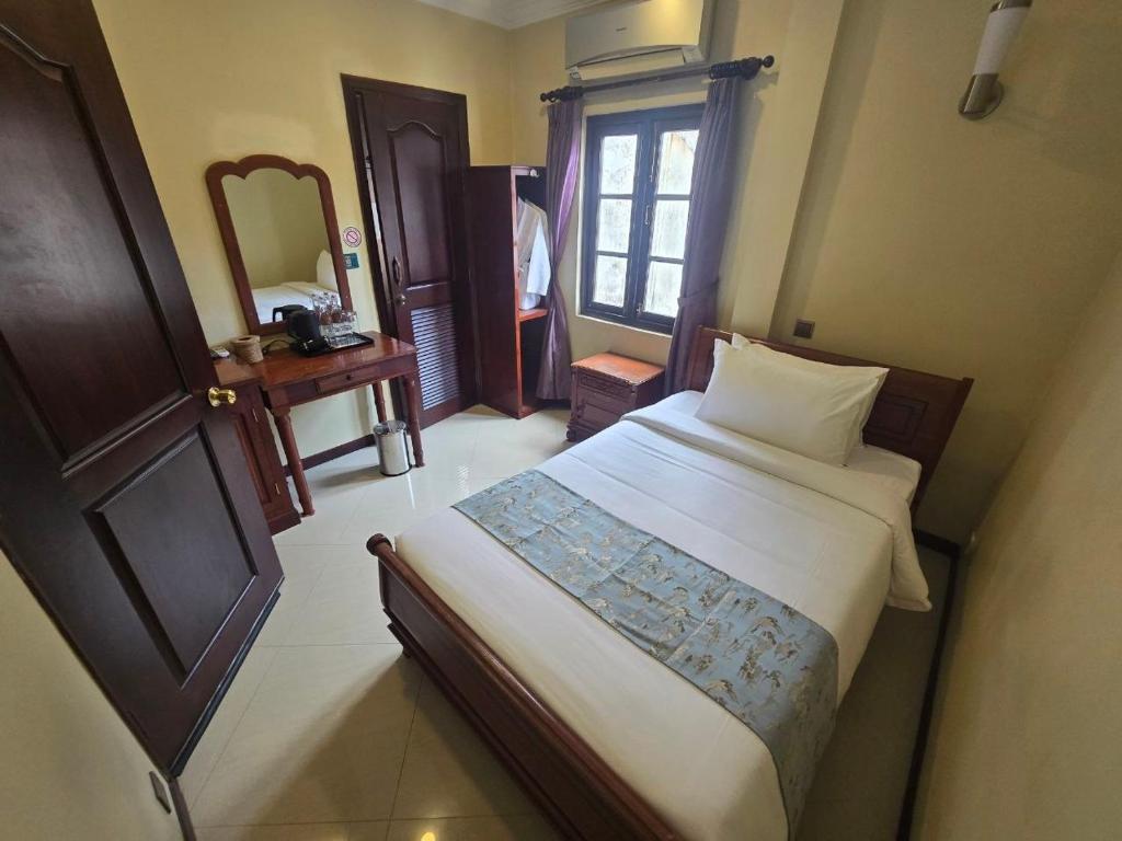 a bedroom with a large bed and a mirror at LT Home Stay in Siem Reap