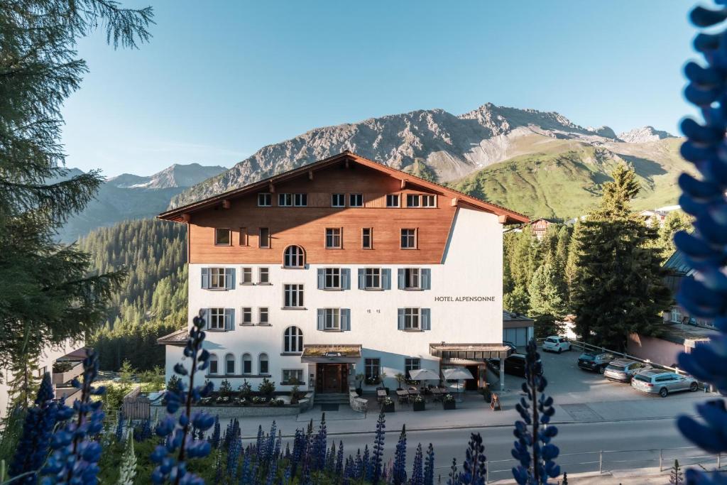 a view of a hotel with mountains in the background at Hotel Alpensonne - Panoramazimmer & Restaurant in Arosa