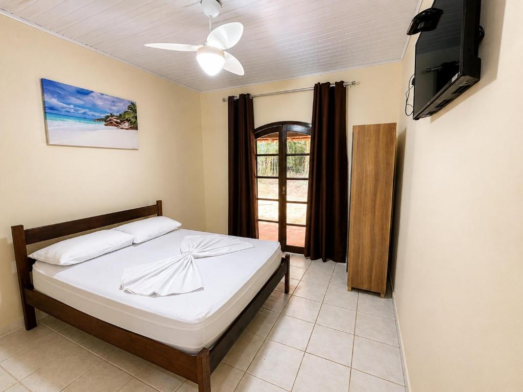 a bedroom with a bed and a tv and a window at Hotel Harmonia Sarapuí in Sarapuí