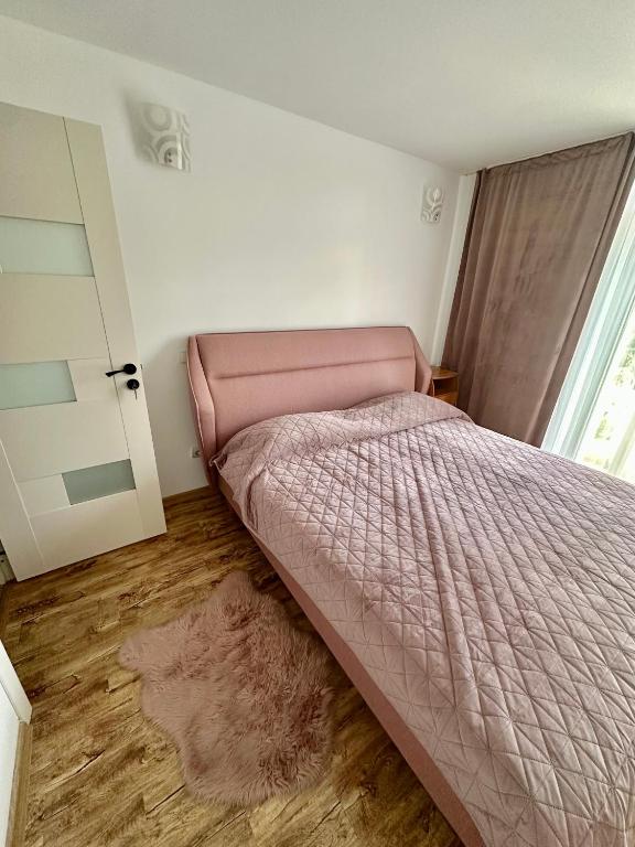 a bedroom with a pink bed and a window at Apartament Uricani in Uricani