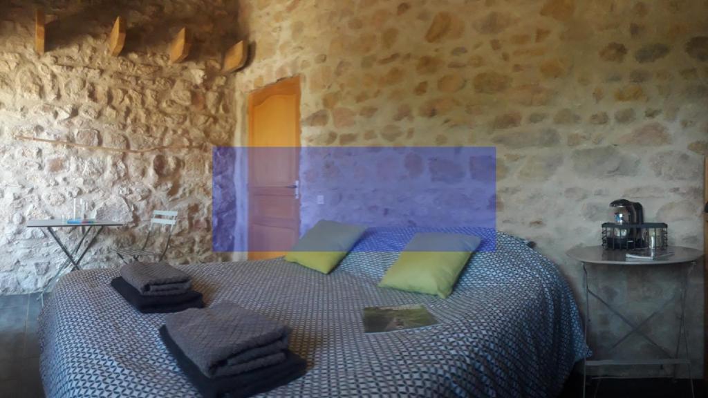 a bedroom with a bed in a stone wall at Nuit pour 4 en Auvergne in Vallon-en-Sully
