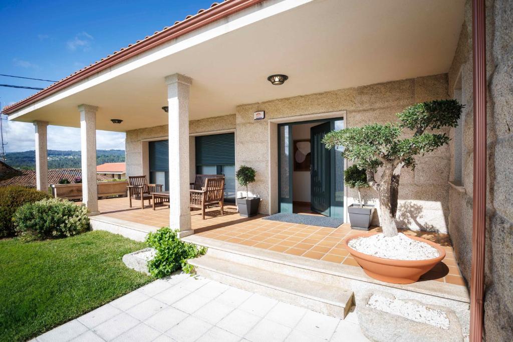 a house with a patio with a tree in a pot at Casa dos olivos in Ourense