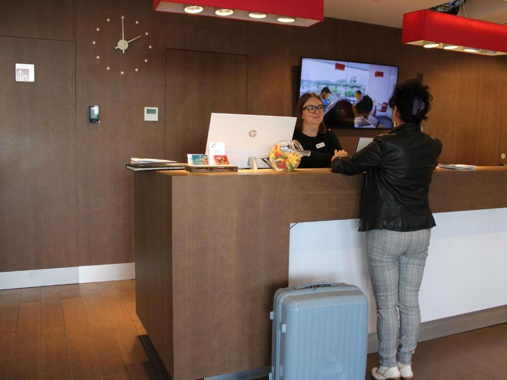 a woman standing at a counter with a woman standing at at Ibis Lleida in Lleida