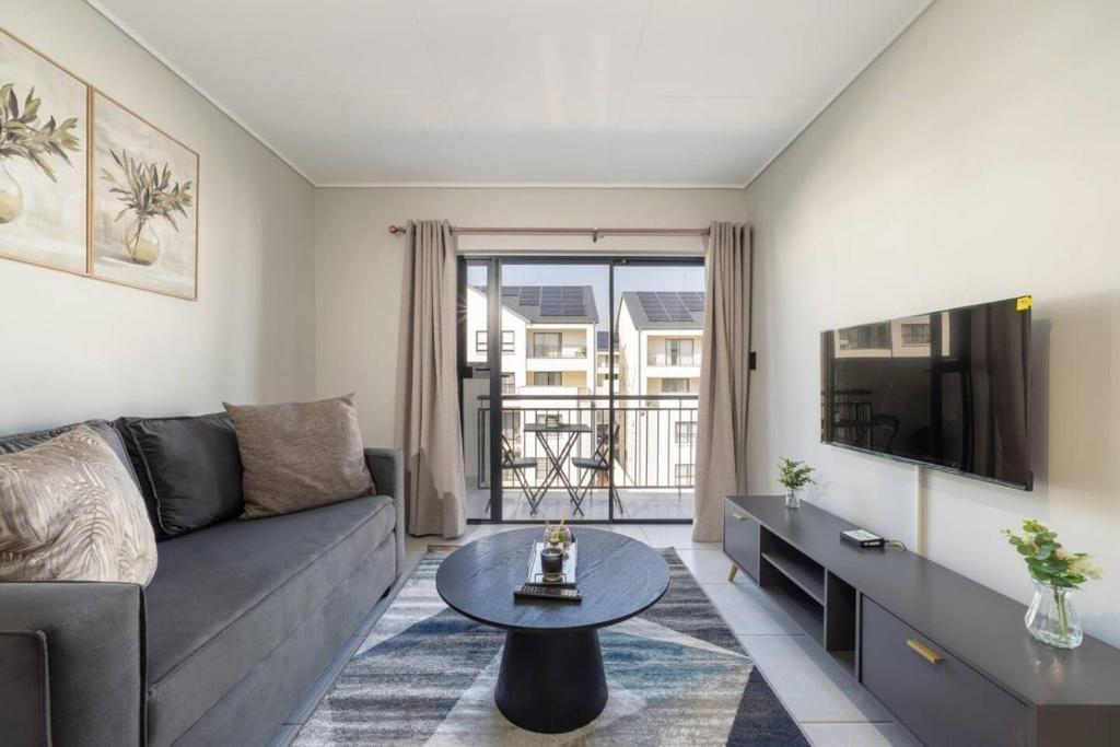 a living room with a couch and a tv at #AlimamaSpaces The Contemporary Retreat in Midrand