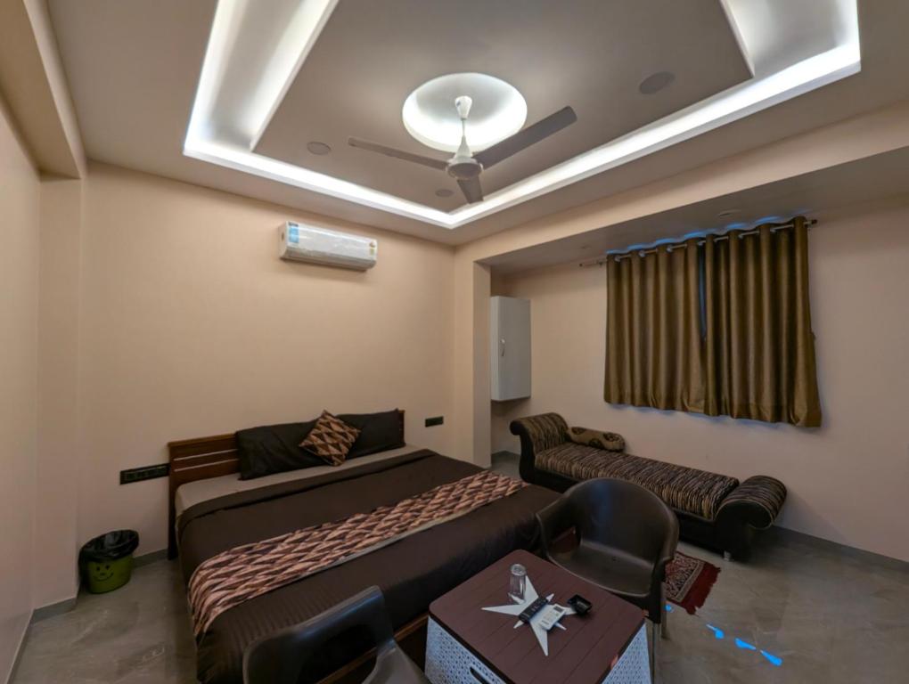 a room with two beds and a couch and a ceiling at Hotel Sai Vandan in Nagpur
