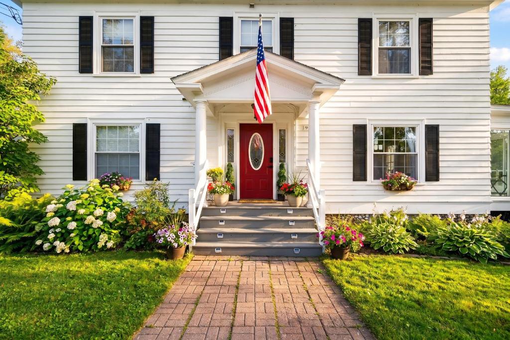 a white house with a red door and an american flag at Launchpoint Lodge in Lincoln