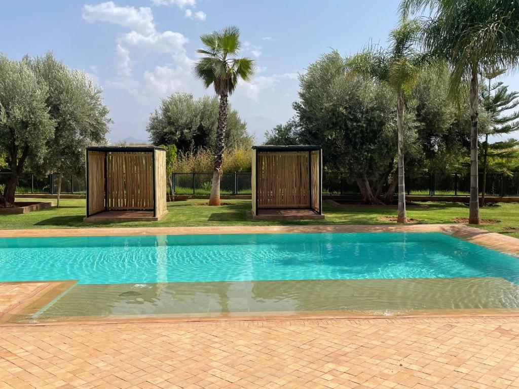 a swimming pool in a yard with palm trees at Olead in Aghmat