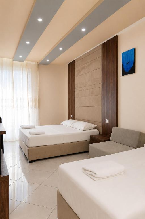 a hotel room with two beds and a couch at AMMEN Rooms in Shëngjin
