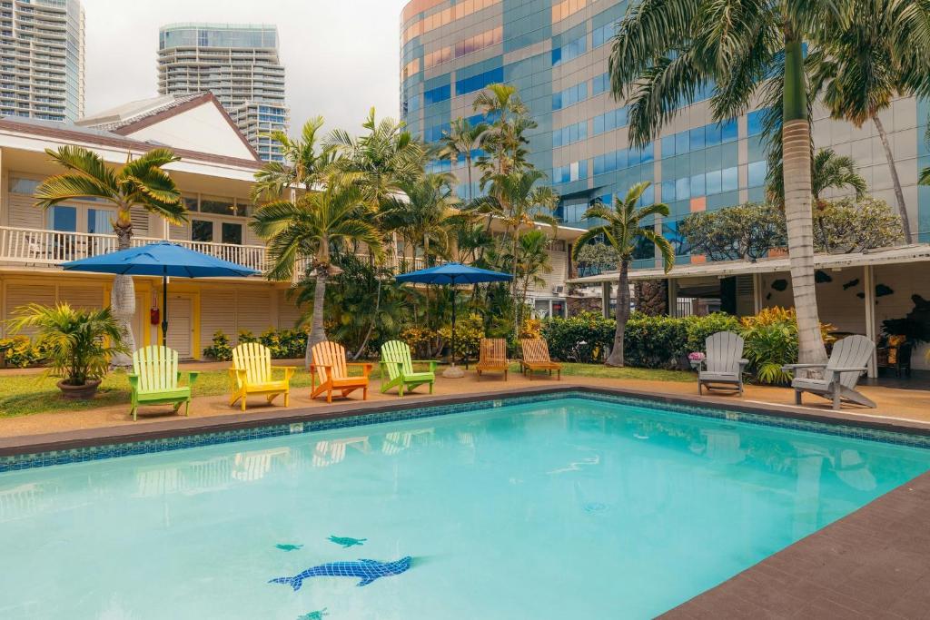 a pool at a hotel with chairs and umbrellas at Waikiki Heritage Hotel in Honolulu