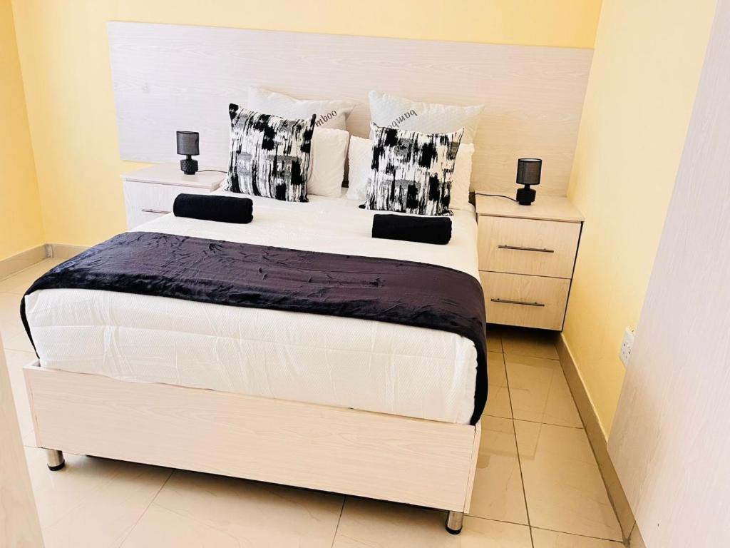 a bedroom with a large white bed with black and white pillows at MrP Guest House in Kokstad