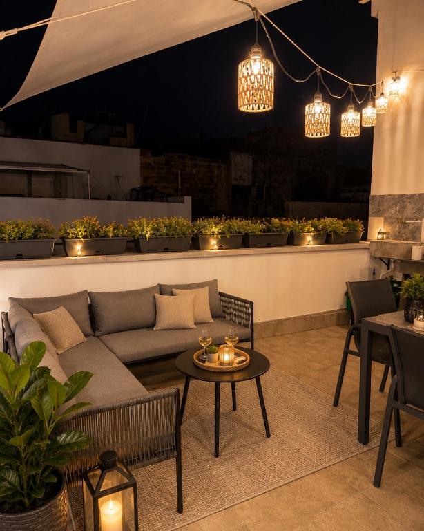 a patio with a couch and a table and lights at La dimora del duomo boutique suites & rooms in Terrasini
