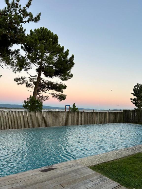 a swimming pool with a tree and a fence at Apartamento playa Illa de Arousa in Isla de Arosa