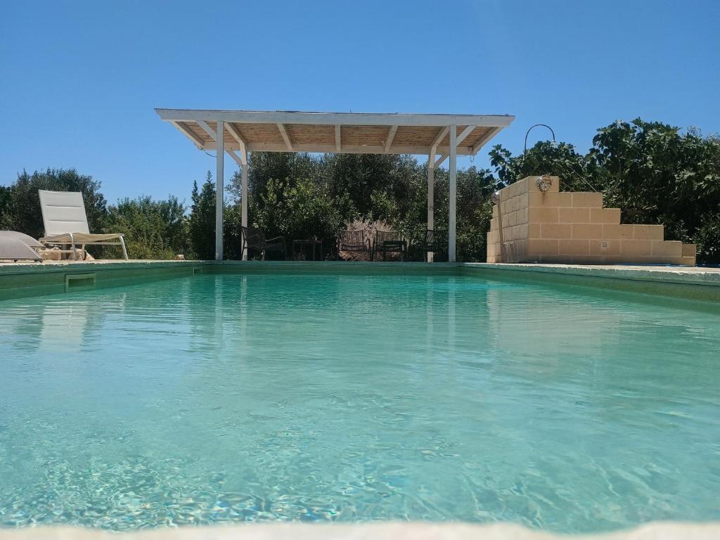 a swimming pool with a pergola over the water at Trullo del Sol in Ceglie Messapica