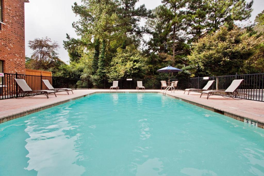 a large swimming pool with chairs and an umbrella at Holiday Inn Express & Suites Buford NE - Lake Lanier by IHG in Buford