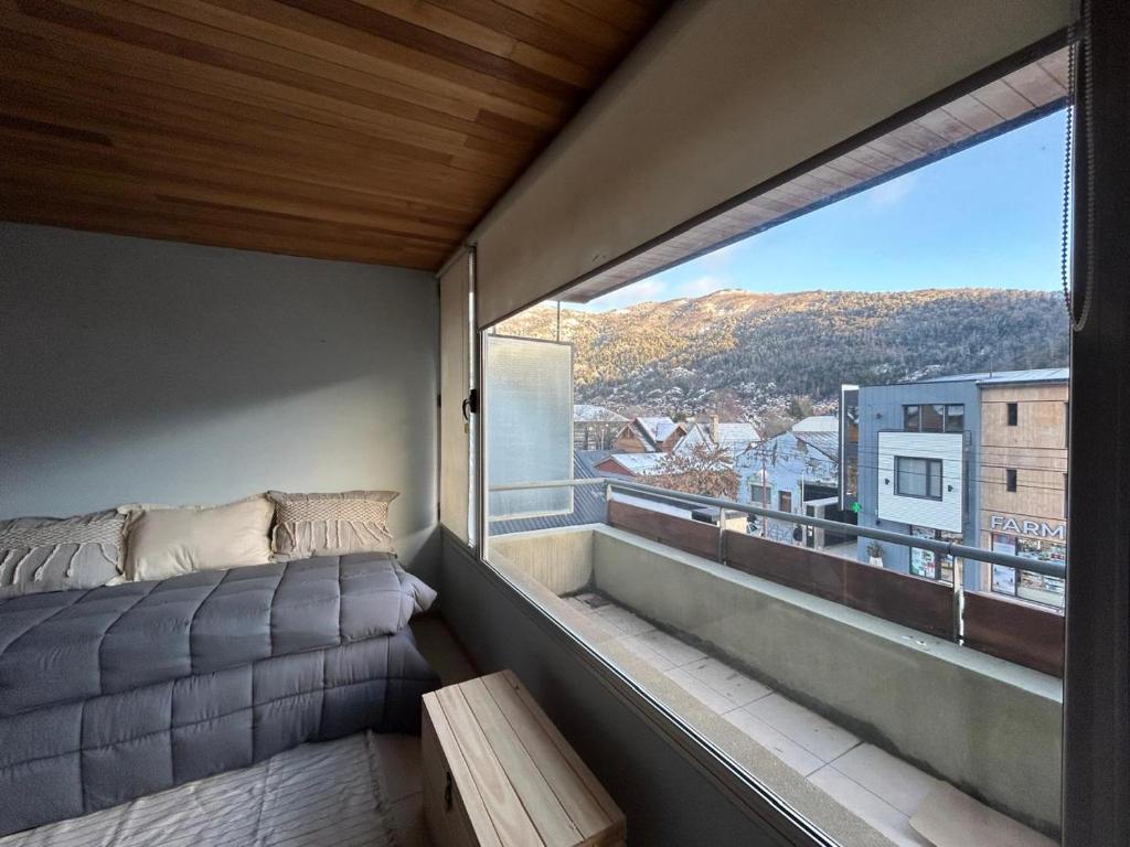 a balcony with a bed and a large window at Dpto General Roca 1355 - La Loggia in San Martín de los Andes
