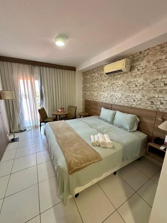 a bedroom with a large bed with two towels on it at Flat em hotel Promenade Itaguaí in Itaguaí