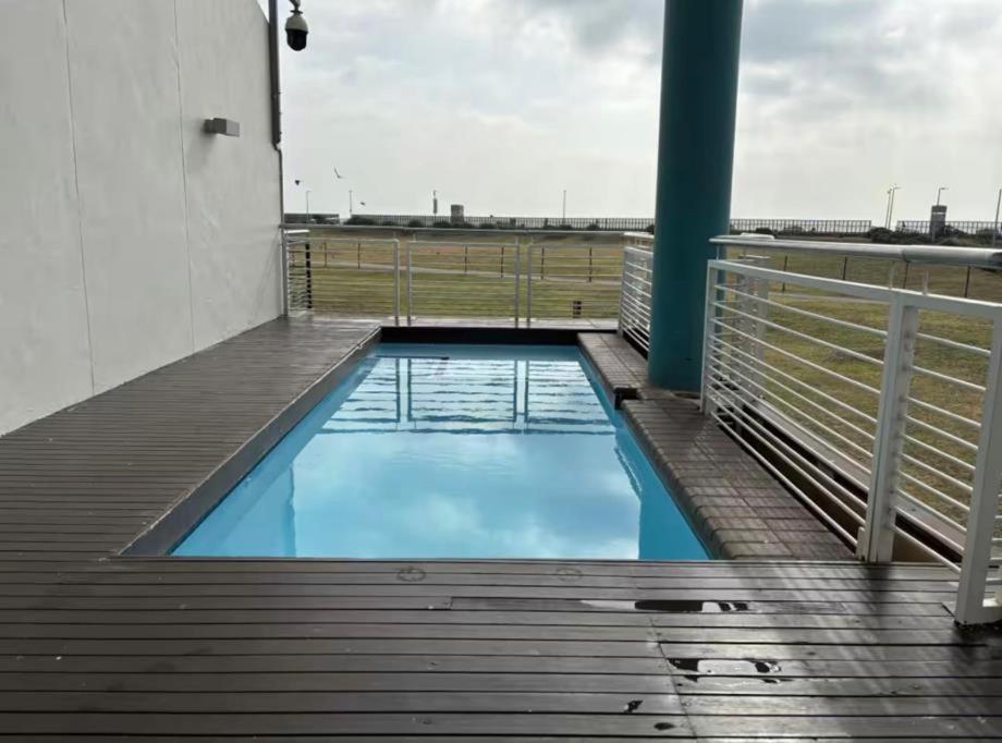 a swimming pool on a wooden deck with a fence at Azure Guesthouse in Ballito