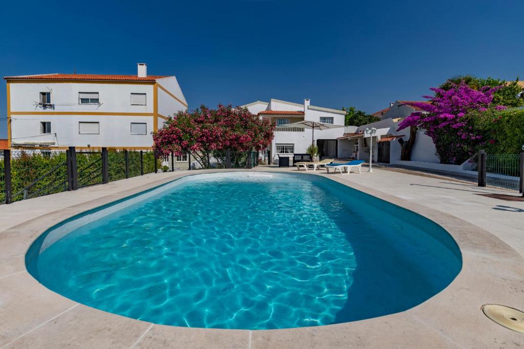 a swimming pool in front of a house at Vivenda Verivitor - Saltwater Pool, Garden, BBQ & Tennis Court in Sesimbra