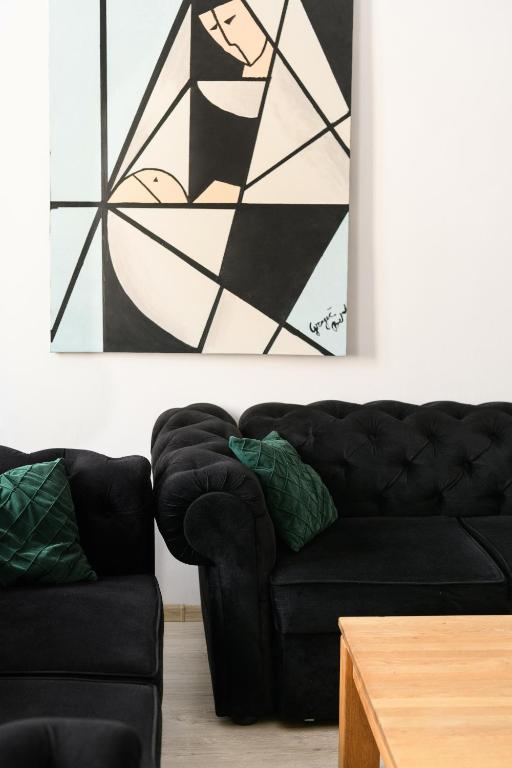 a living room with a black couch and a painting at CARLA comfort stay with 2 bathrooms in Košice