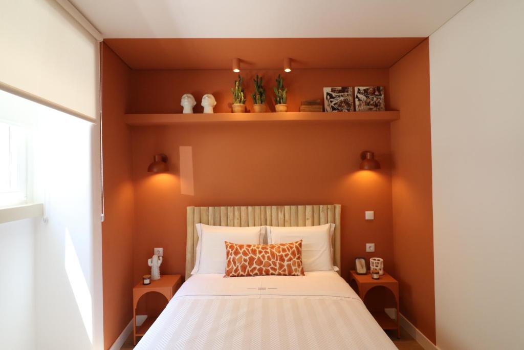 a bedroom with a large bed with orange walls at Tinico's Guest Rooms in Nazaré
