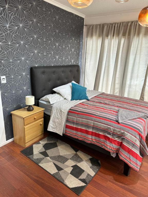 a bedroom with a bed and a nightstand with a bed sidx sidx sidx sidx at Alojamientos Quintamar Viña in Viña del Mar