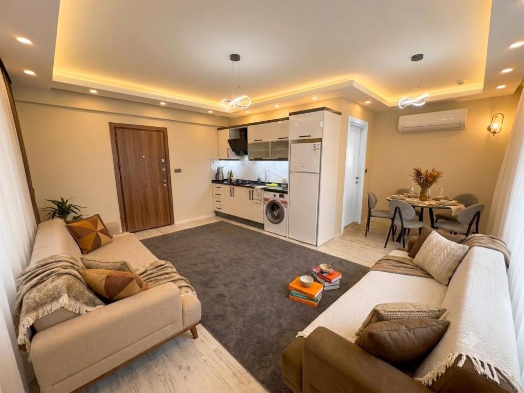 a living room with two couches and a kitchen at Alas Garden City Apartment Fethiye in Fethiye