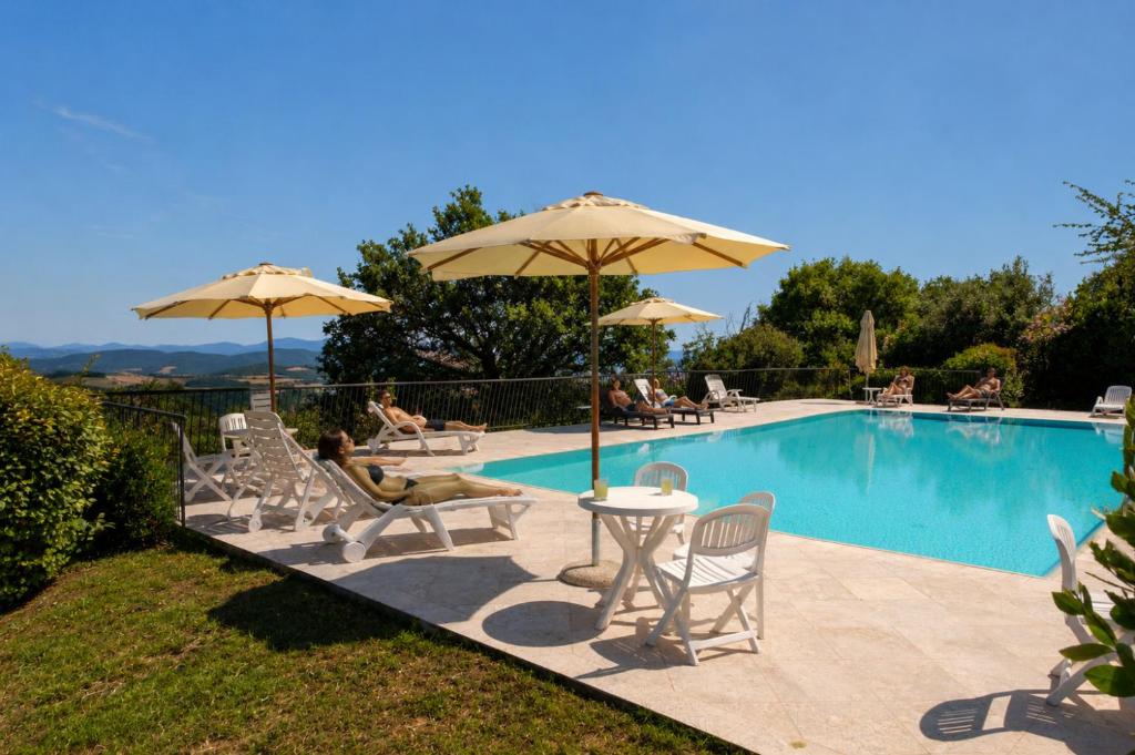 a swimming pool with chairs and umbrellas next to a pool at Relais Villa Sensano in Pignano