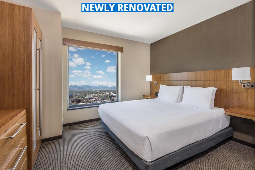 a large bed in a hotel room with a large window at Hyatt Place Denver Downtown in Denver