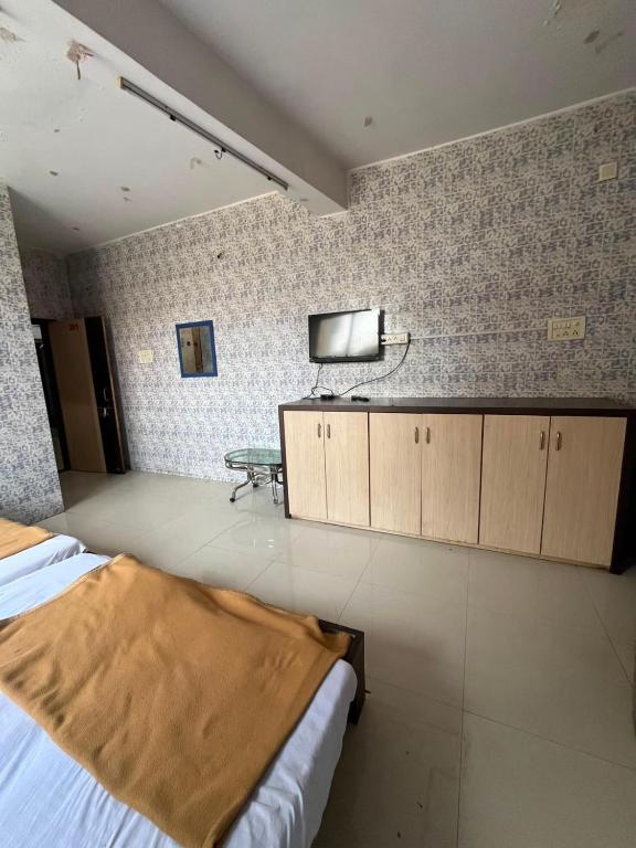 a bedroom with a bed and a tv on the wall at Hotel Novex in Rajkot