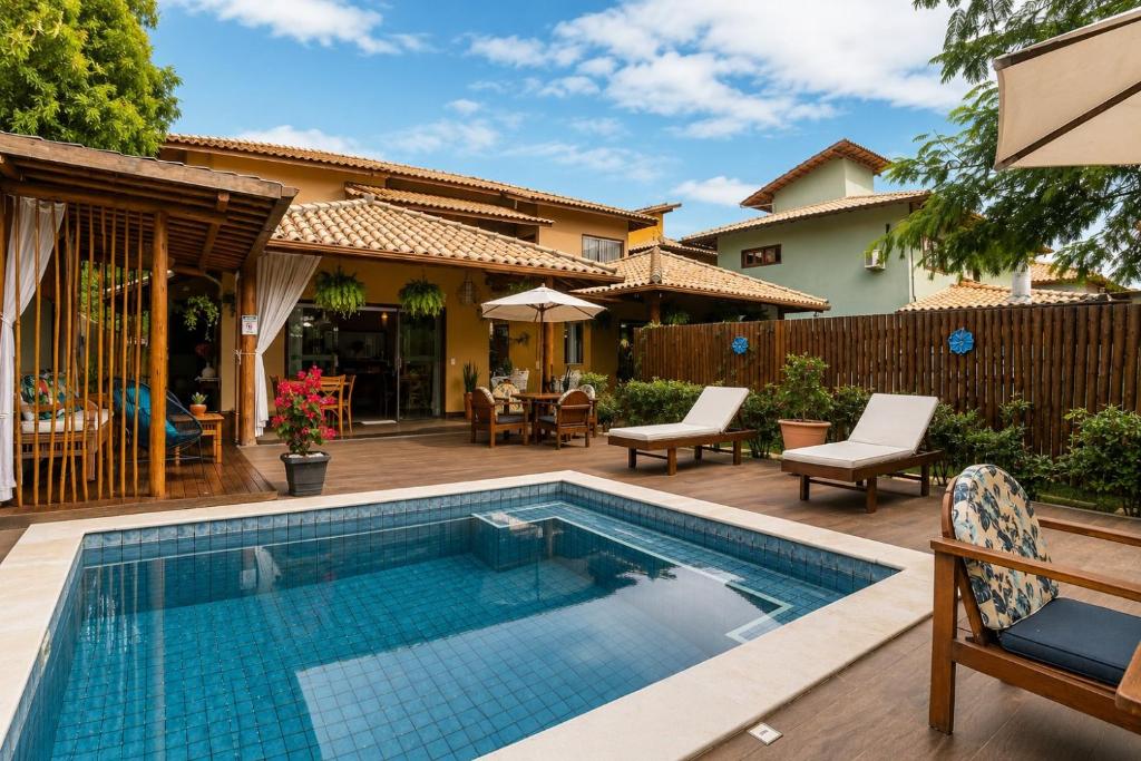 a swimming pool with a patio and a house at Pousada Casa Cajá in Arraial d'Ajuda