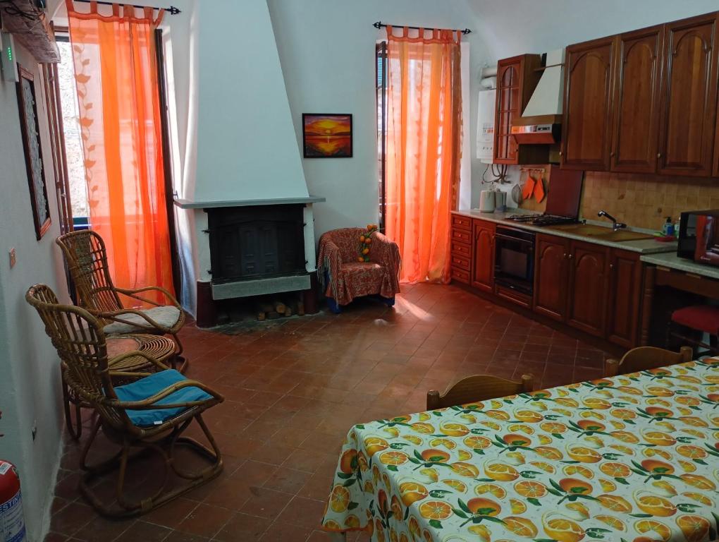 a kitchen with orange curtains and a table and a fireplace at Casa Arancia in Isolabona