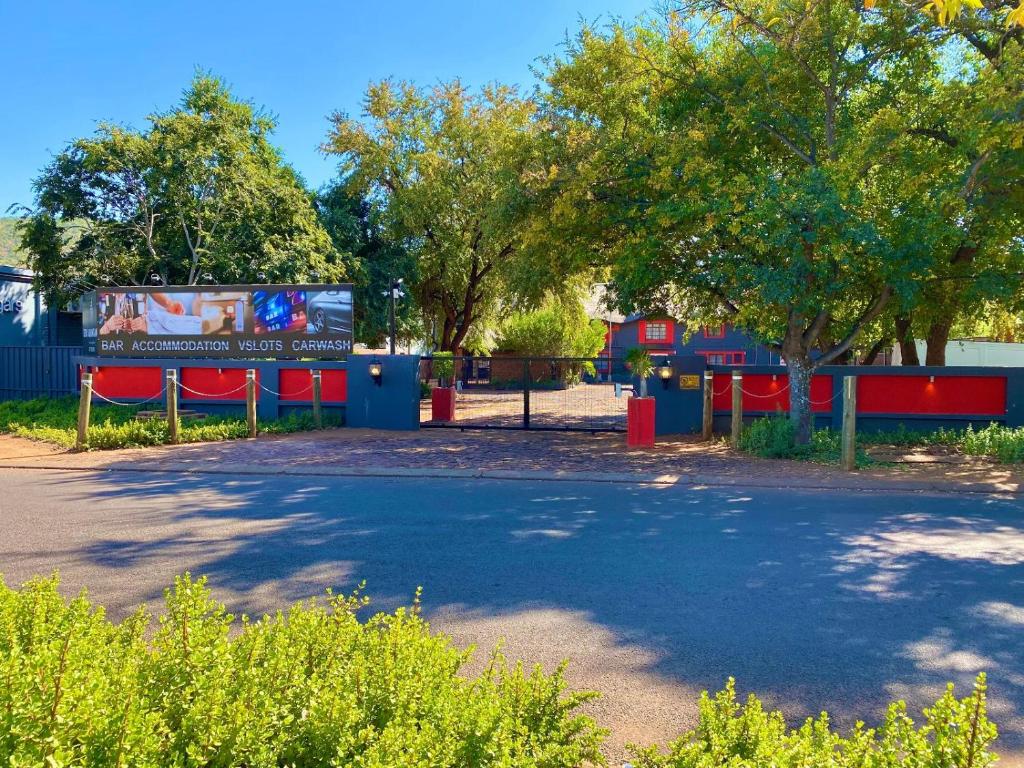 a playground in a park with trees and a sign at Echo Mountain Inn in Thabazimbi
