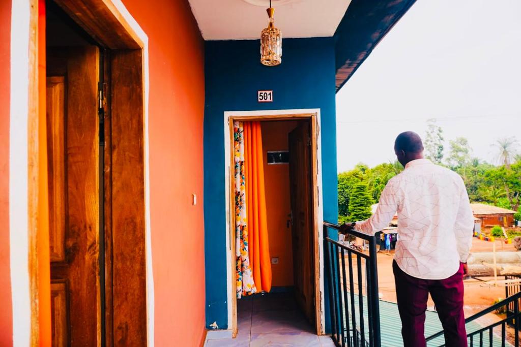 a man standing on a balcony of a house at point de distraction in Foumban