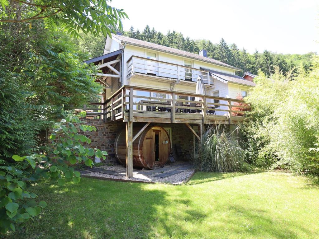 a large house with a deck in a yard at Le Moulin de Rendeux in Rendeux