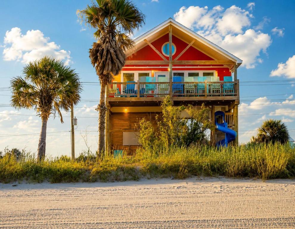 a house on the beach with palm trees at Beachfront Luxe, Ocean Views, Hot tub, Firepit, Sleeps 14 in Bolivar Peninsula