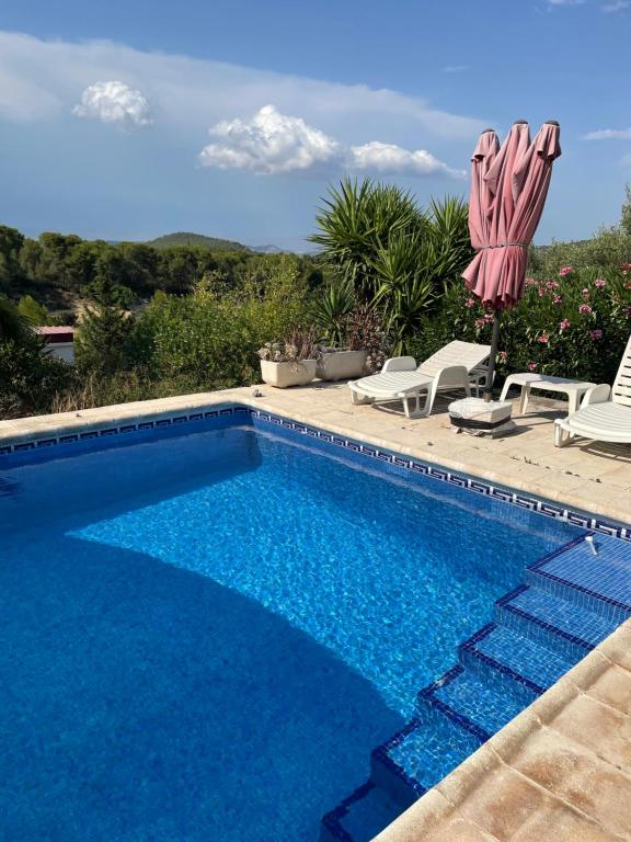 a swimming pool with two chairs and an umbrella at Casita Ramona in Valencia