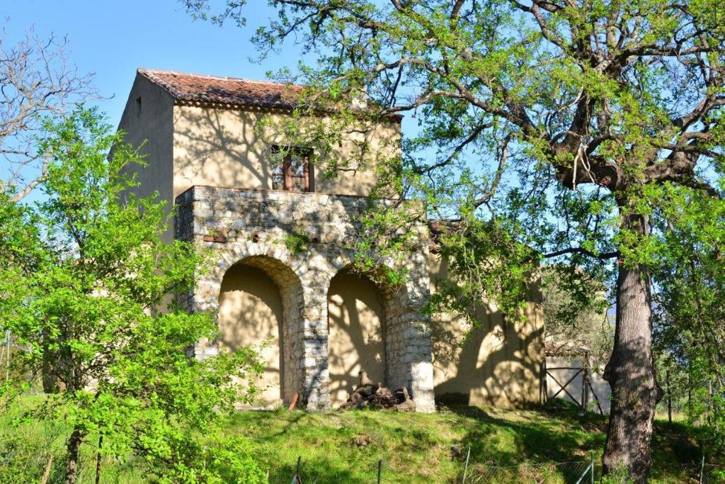 an old stone house on a hill with trees at Loggia dei Barbaggianni in Torraca