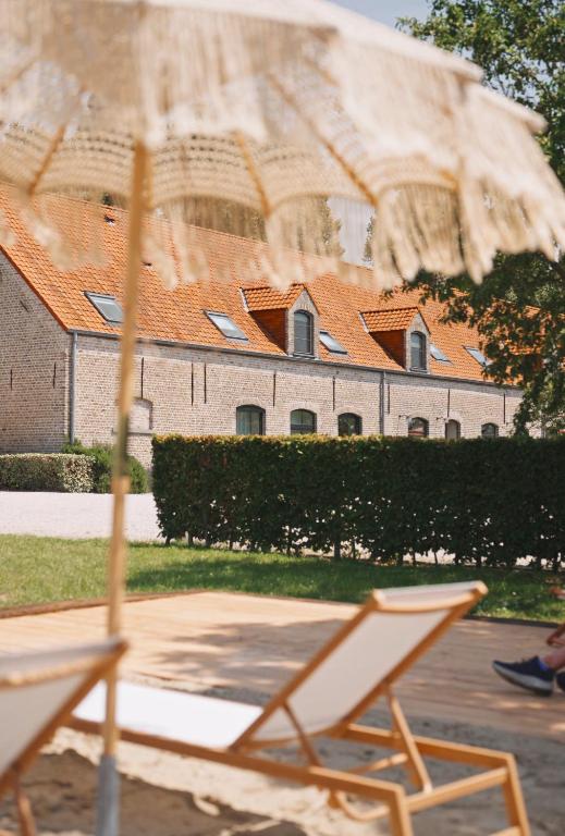 a chair and an umbrella in front of a building at Hoeve Hazegras in Knokke-Heist