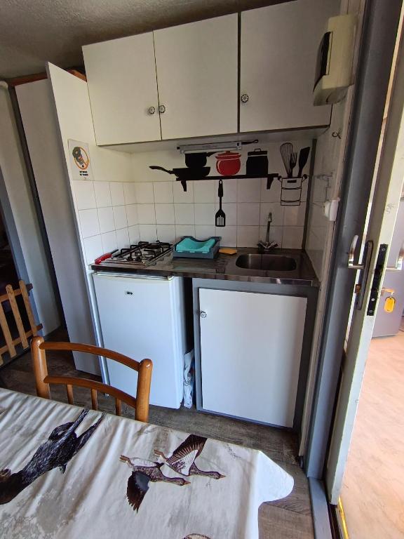 a small kitchen with white cabinets and a sink at Camping du lac chalet P62 in Foix