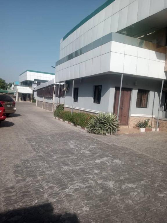 a white building with a parking lot in front of it at Luxritel Hotel Abuja in Kajewole