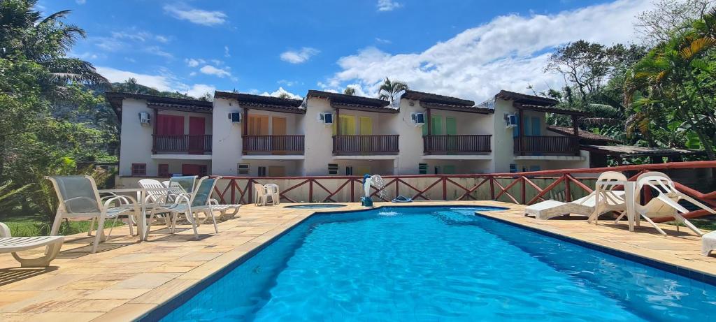 a hotel with a swimming pool and chairs and a building at Arco Iris Chales II in Maresias