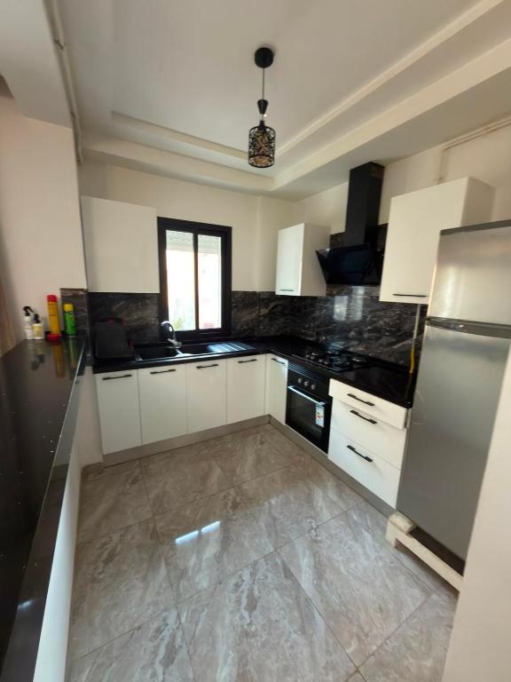 a kitchen with white cabinets and black appliances at Appartement de luxe in Tunis