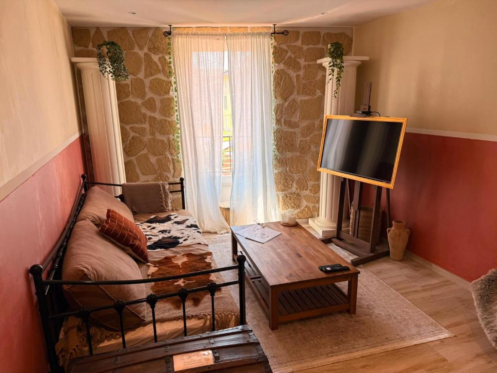 a living room with a bed and a table and a television at L'Escale Romaine - Expérience Antique Unique - Centre Historique Orange in Orange