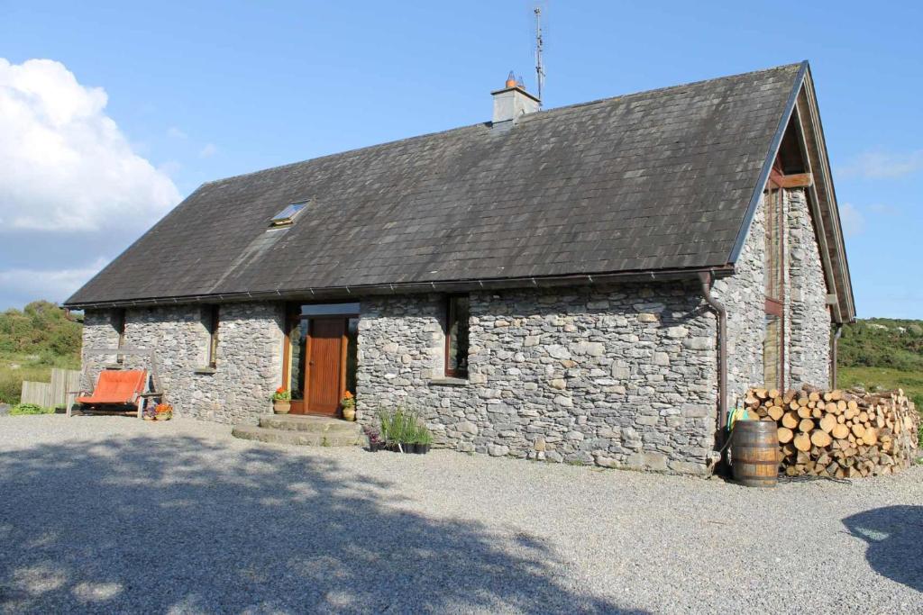 a small stone building with a pile of logs at Beautiful Stone Riverside Retreat Galway in Galway