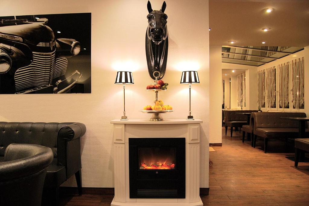 a living room with a fireplace and a picture of a car at Hotel Krone Aachen | City-Eurogress in Aachen