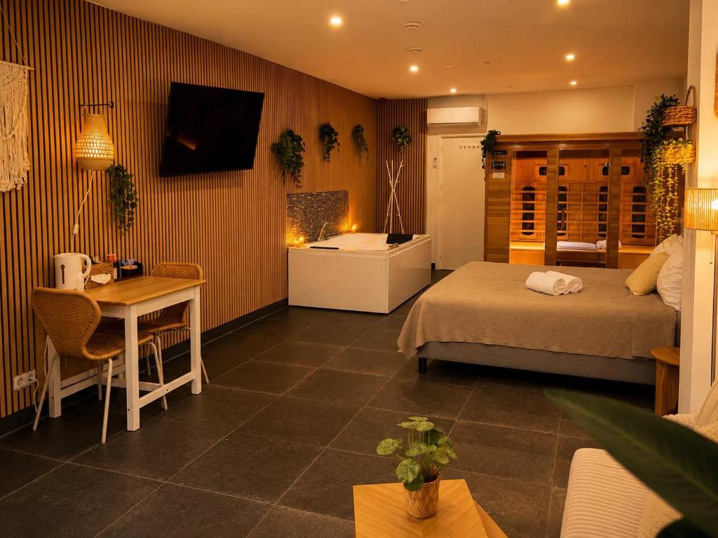 a bedroom with a bed and a table and a desk at Wellness Suite Zeist in Zeist