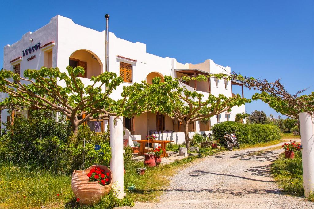 a white building with trees and flowers in front of it at Aeolos seaside studios in Frangokastello