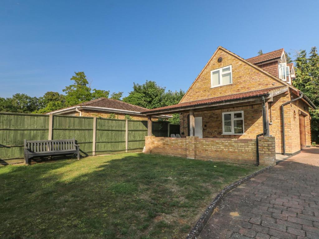 a house with a fence and a bench in the yard at Thames Retreat in Staines upon Thames